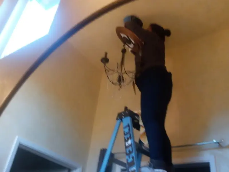 Electrician installing a chandelier in a Plantation residence